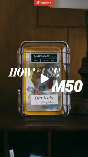 나무 책상 위 M50 마이크로 케이스. 안에 노란 그림과 "Orchids by Minjinlee"라 쓴 쪽지가 들어 있다