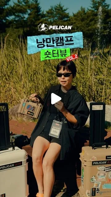 억새밭에서 작은 케이스를 든 여자. 양옆에 펠리칸 에어 케이스가 놓여 있고 "낭만캠프 숏터뷰 VOL.2" 글자